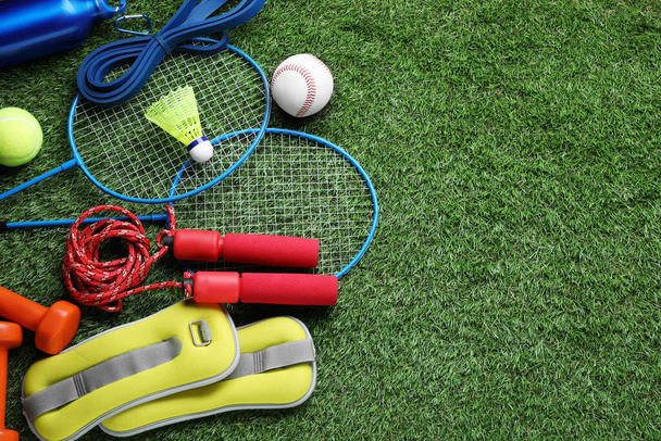 Set of different colorful sports equipment on green grass, above view. Space for text - Zdjęcie, obraz