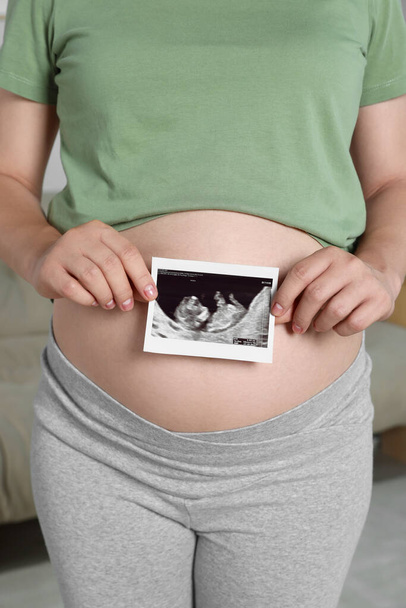 Pregnant woman with ultrasound picture of baby in room, closeup - Фото, зображення