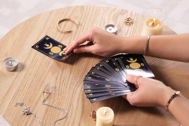 Soothsayer predicting future with tarot cards at table indoors, closeup - Photo, image