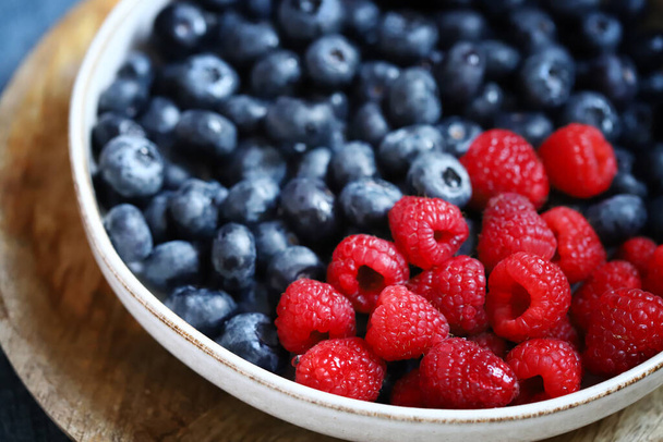 Fresh selected raspberries and blueberries in a bowl. Healthy snack. Berries for dessert. Close-up. - Photo, Image