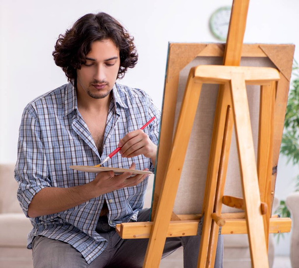 Il giovane bell'uomo si diverte a dipingere a casa
 - Foto, immagini