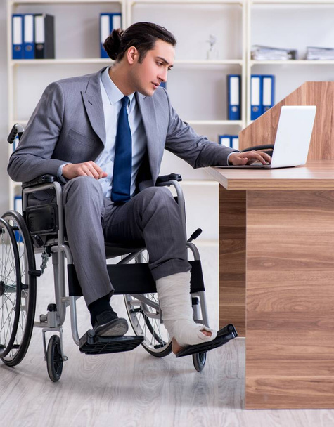 Ofisteki tekerlekli sandalyedeki erkek çalışan. - Fotoğraf, Görsel