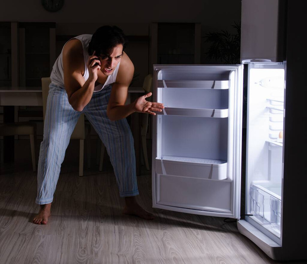 Ο άνθρωπος που σπάει τη δίαιτα τη νύχτα κοντά στο ψυγείο - Φωτογραφία, εικόνα