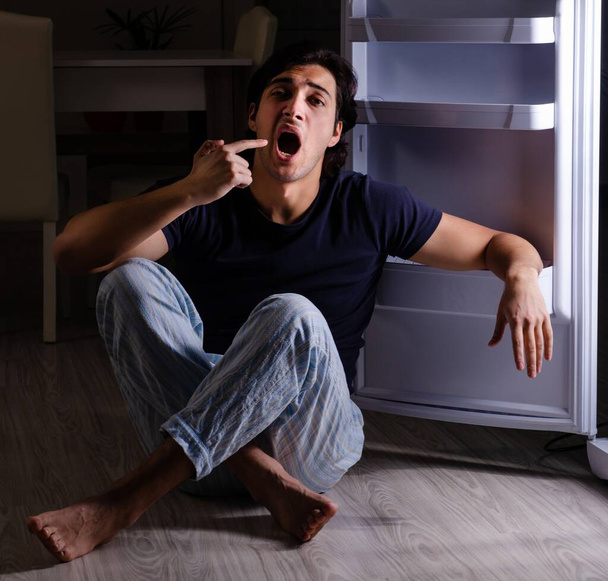Mies, joka rikkoo ruokavaliota yöllä lähellä jääkaappia - Valokuva, kuva