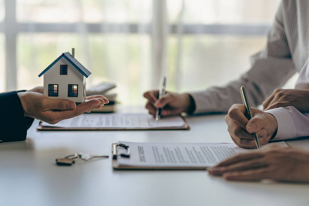 ingatlan ügynökök tárgyalni Megvitassák a feltételeket a kamatláb megállapodás megvásárlására egy otthon részletekben. és kérje meg az ügyfeleket, hogy írják alá a szerződést - Fotó, kép