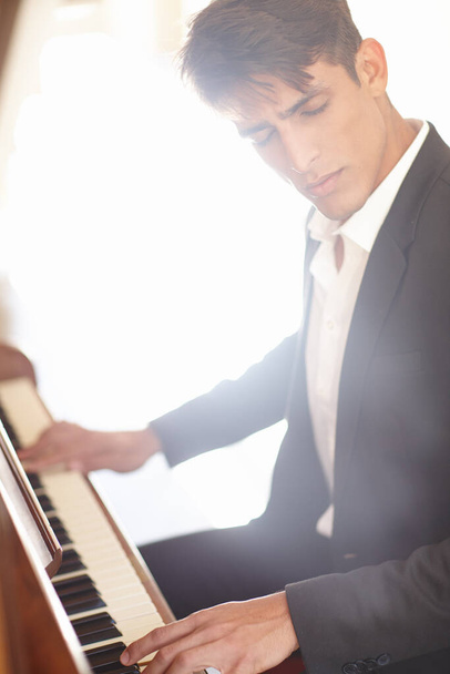 У него настоящий дар. красивый молодой человек выглядит вдохновленным, играя на фортепиано - Фото, изображение
