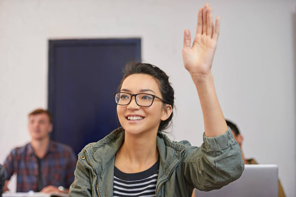 Hyödynnetään hänen koulutustaan. nuori nainen nostaa kätensä kysyäkseen kysymyksen luokassa - Valokuva, kuva