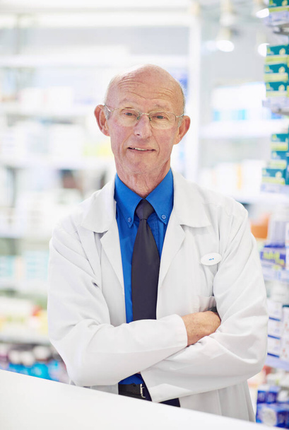 Está aquí para ayudar con años de experiencia. Retrato de un farmacéutico senior trabajando en un mostrador - Foto, imagen