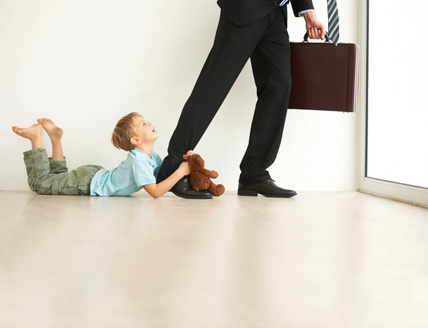 No, dont go. A little boy on the floor, very unhappy that his faher is leaving for work - Foto, imagen