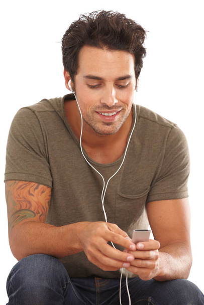 À procura da sua faixa favorita. Um jovem bonito ouvindo música em seu mp3 player isolado no branco - Foto, Imagem
