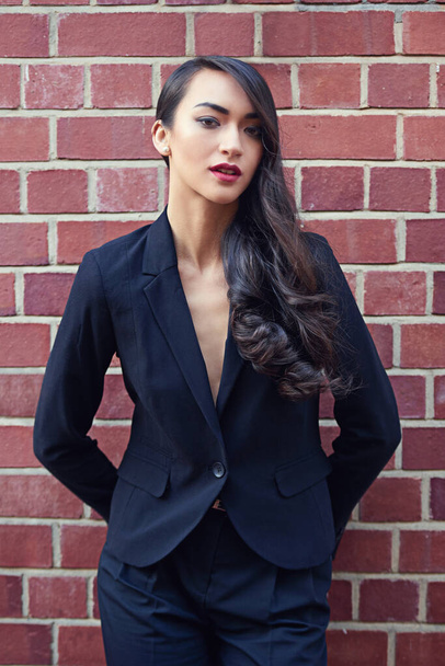 Sartorialist style. a beautiful woman wearing a classic feminine suit leaning against a brick wall - Fotó, kép
