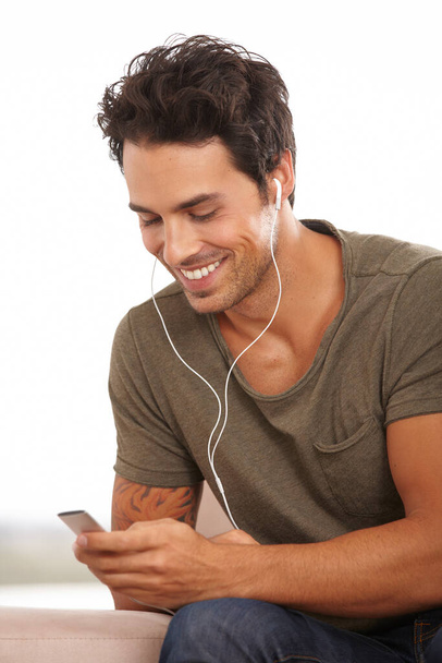 Мені подобається ця пісня. Гарний молодий чоловік слухає музику на своєму mp3 плеєрі ізольовано на білому
 - Фото, зображення