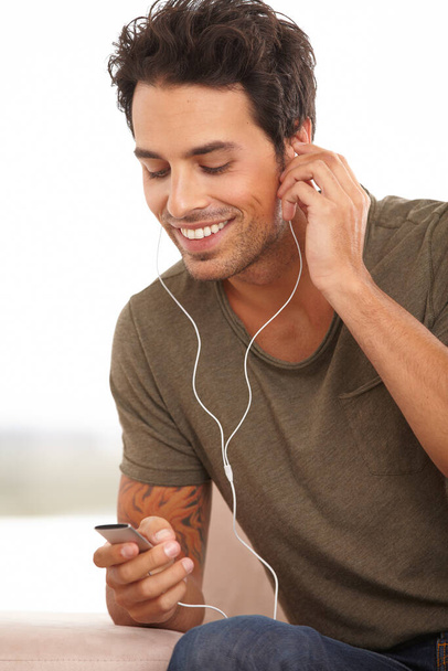 Mi canción favorita. Un joven guapo escuchando música en su reproductor de mp3 aislado en blanco - Foto, Imagen