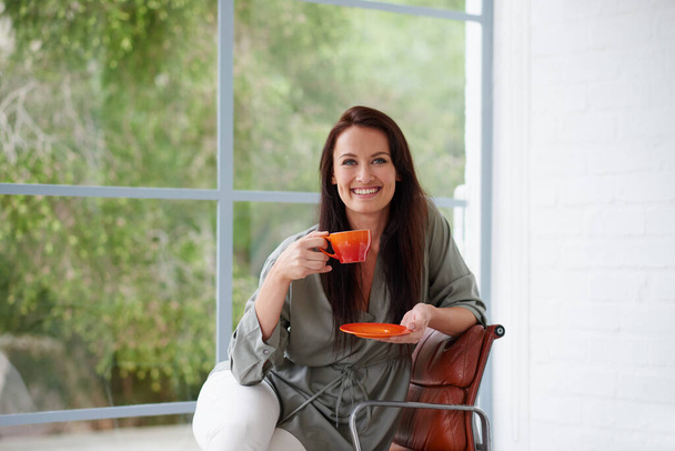 Disfrutando de su café de la mañana. Una joven mujer relajándose en su sala de estar - Foto, Imagen