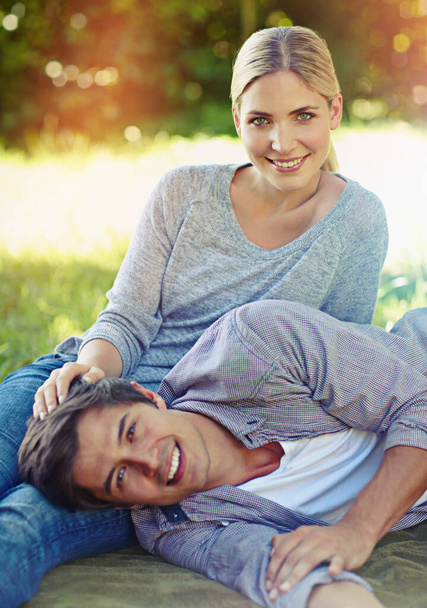 Love at leisure. a happy young couple lying on the grass and sharing an affectionate moment together - Photo, Image