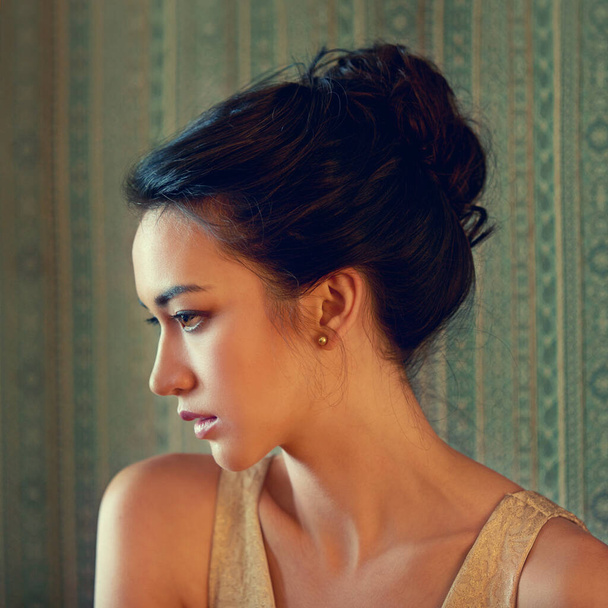 Sensual beauty of another era. Profile shot of a beautiful young woman dressed elegantly indoors - Фото, изображение