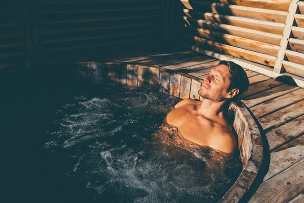 Man relaxing in wooden hot tub outdoor. . High quality photo - Foto, Bild