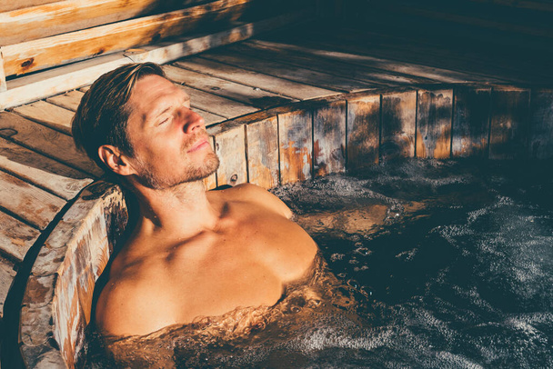 Man relaxing in wooden hot tub outdoor. . High quality photo - Foto, Bild