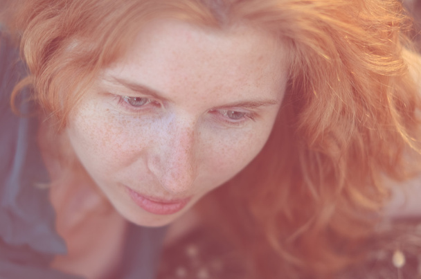 Closeup of red-haired girl with freckles looking down. - Photo, Image