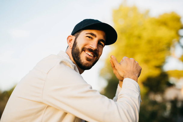 Portrait of a young bearded man wearing a black cap at countryside - Photo, Image