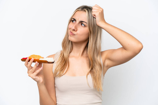 Young caucasian woman holding sashimi isolated on white background having doubts and with confuse face expression - Fotografie, Obrázek