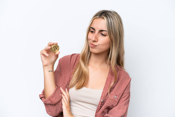 Young caucasian woman holding a Bitcoin isolated on white background with sad expression - Foto, Bild