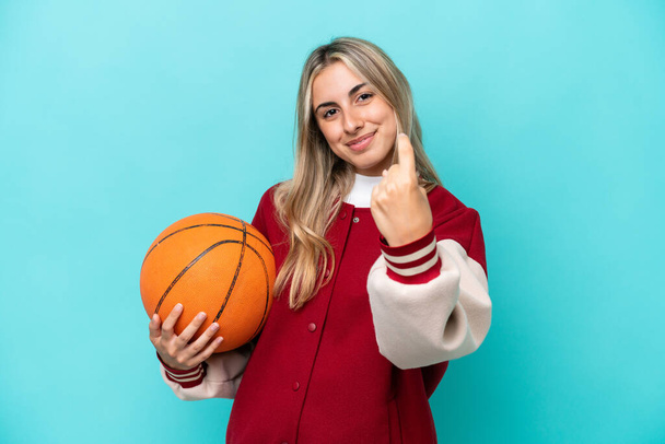 Young caucasian basketball player woman isolated on blue background doing coming gesture - Фото, зображення