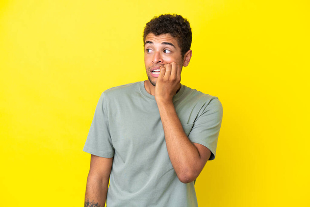 Young handsome Brazilian man isolated on yellow background is a little bit nervous - Photo, Image