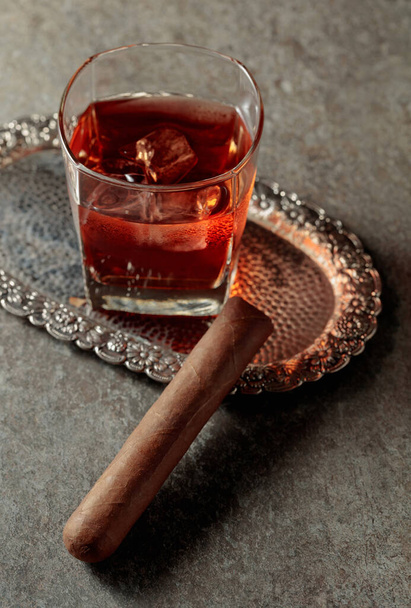 Whisky con hielo y cigarro en una vieja mesa de piedra. Copiar espacio. - Foto, Imagen