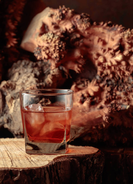 Whiskey with ice on an old dried stump. Copy space. - Фото, изображение