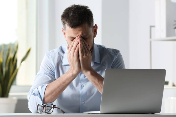 Man suffering from eyestrain at desk in office - Фото, зображення