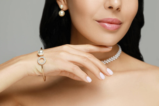 Young woman wearing elegant pearl jewelry on grey background, closeup - Photo, image