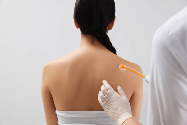 Woman undergoing physiotherapy procedure with darsonval in salon, back view - Foto, Imagen