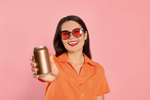 Beautiful young woman holding tin can with beverage on pink background - Foto, Bild