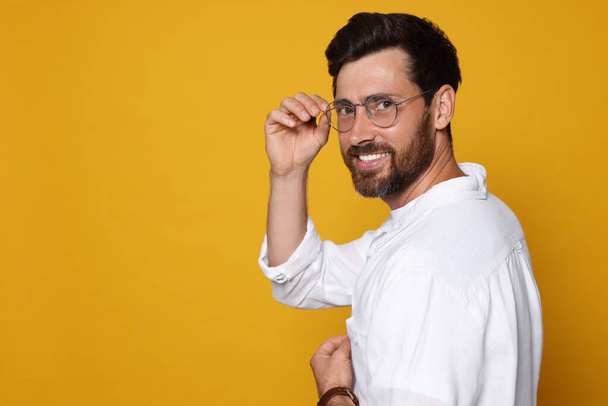 Portrait of smiling bearded man with glasses on orange background. Space for text - Fotografie, Obrázek