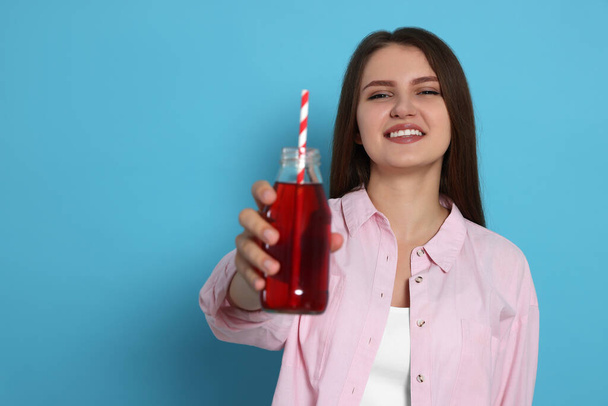 Beautiful young woman with glass bottle of juice on light blue background. Space for text - Φωτογραφία, εικόνα