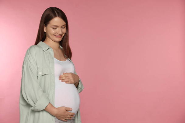 Happy young pregnant woman on pink background. Space for text - Valokuva, kuva