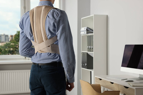 Closeup of man with orthopedic corset in room, back view - Foto, imagen