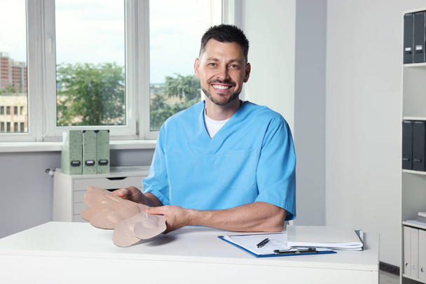Handsome male orthopedist showing insoles in hospital - Photo, Image