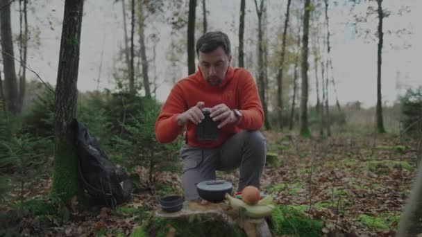 Traveler mounts kitchen gear for cooking. Compact and portable cuisine. Folding camping gas campfire system with gas and pot for quick heating. Man gets ready for heating water on gas stove in woods.  - Footage, Video