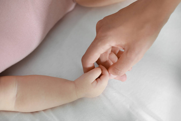 Baby holding mother?s hand on bed, closeup - Foto, Imagem