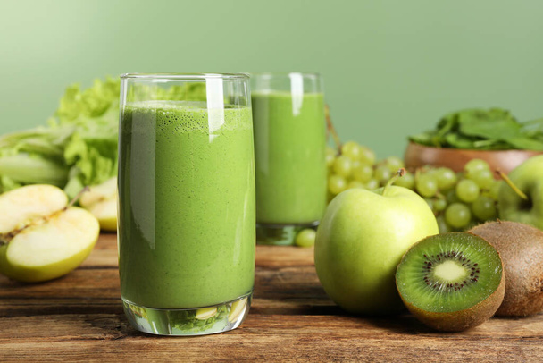 Green smoothie and fresh ingredients on wooden table - Foto, Imagem