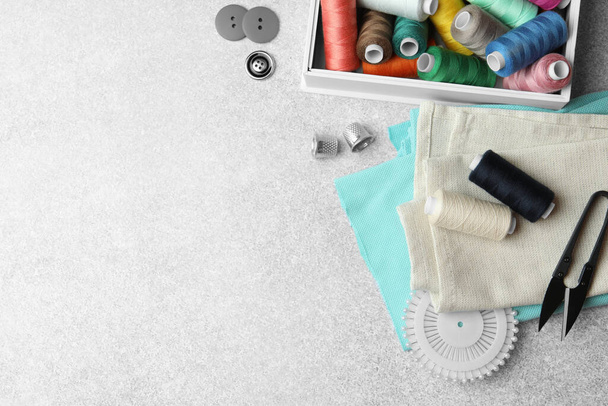Flat lay composition with spools of threads and sewing tools on light background, space for text - Foto, Imagem