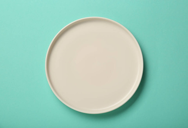 Empty ceramic plate on turquoise background, top view - Foto, Bild