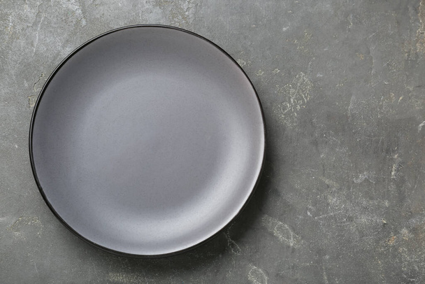 Empty ceramic plate on grey table, top view. Space for text - Zdjęcie, obraz