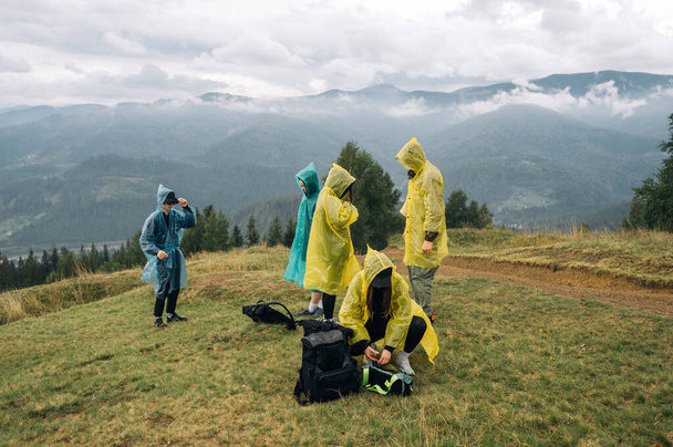 Bir grup turist bir dağ tezgahının tepesine çıkıp bulutlu ve sisli gerçek dışı manzaralara karşı yürüyüş yapmaya hazırlanıyorlar.. - Fotoğraf, Görsel