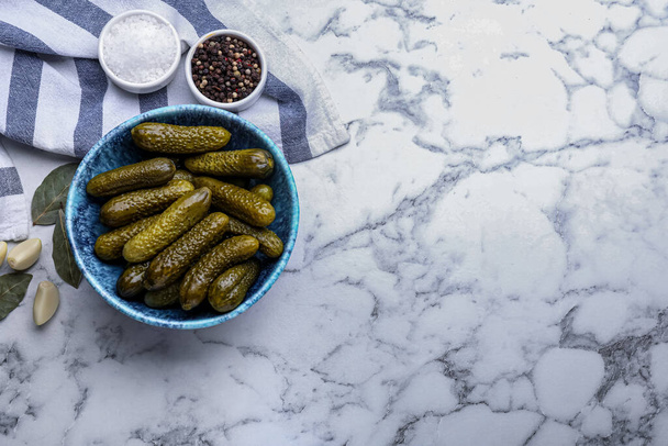 Bowl of pickled cucumbers and ingredients on white marble table, flat lay. Space for text - Φωτογραφία, εικόνα