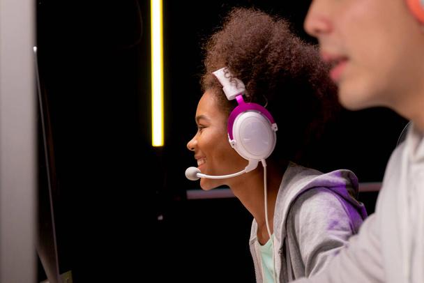 Junge Afroamerikanerin und asiatischer Mann mit Headset spielen Videospiel und Live-Streaming online mit Mikrofon, Gaming und E-Mail für Wettbewerb oder Casting-Spiel, Unterhaltungskonzept. - Foto, Bild