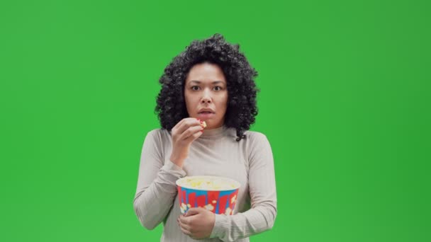 Αφροαμερικανή φοβισμένη γυναίκα τρομοκρατημένη τρώγοντας ποπ κορν βλέποντας την ιδέα ταινιών τρόμου ή θρίλερ απομονωμένη στην πράσινη οθόνη - Πλάνα, βίντεο