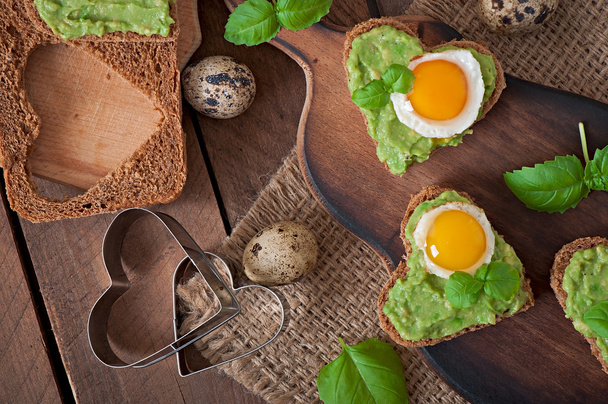 Sandwich with avocado paste and egg in the shape of heart - Foto, afbeelding